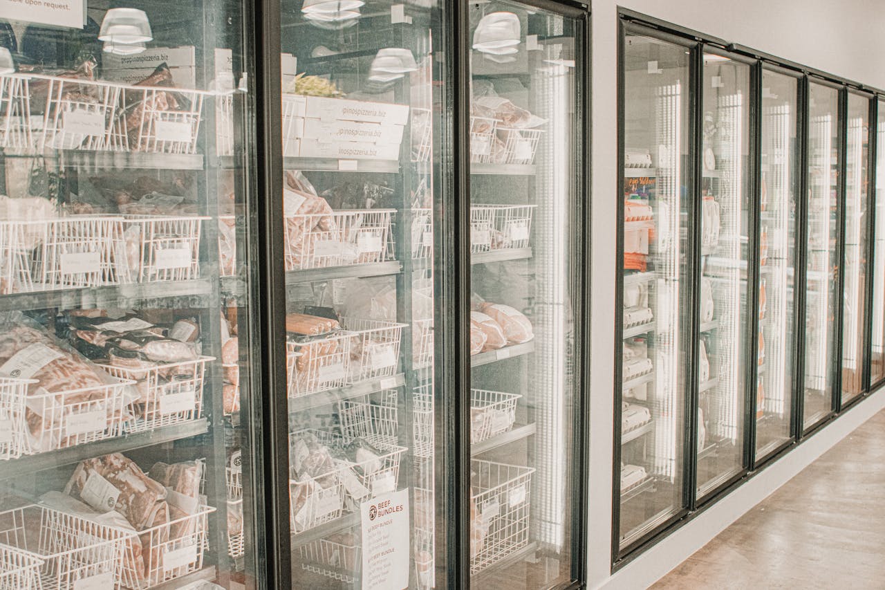 why-choose-us-02 Frozen meats in a retail freezer with transparent doors and organized sections.